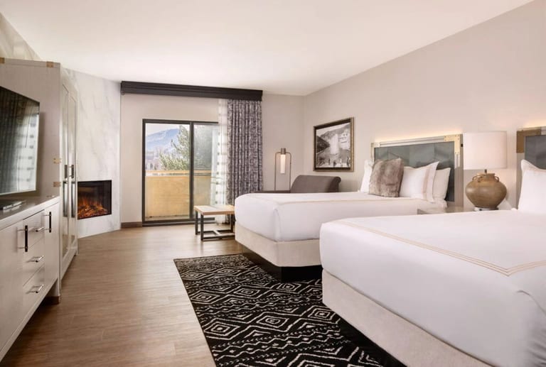 A finished hotel guest room with two beds and a corner fireplace