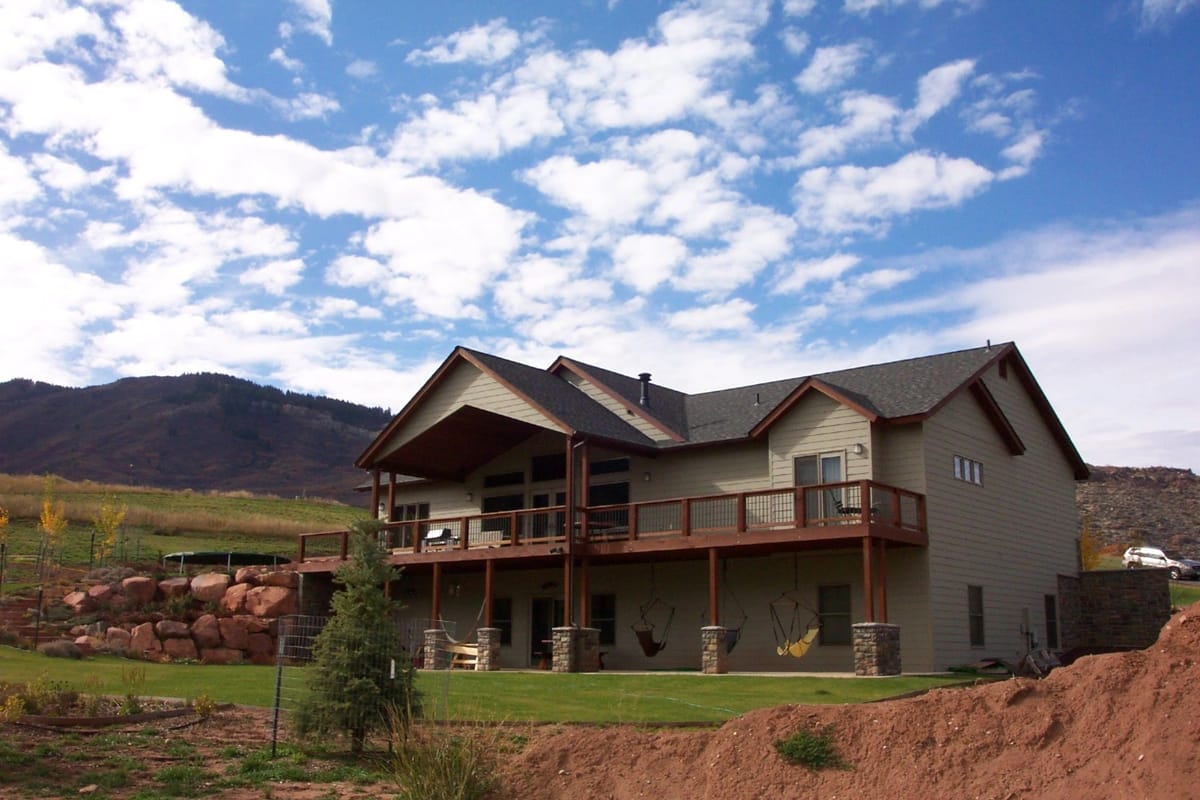 A home with a wraparound deck built above a red-rock cut