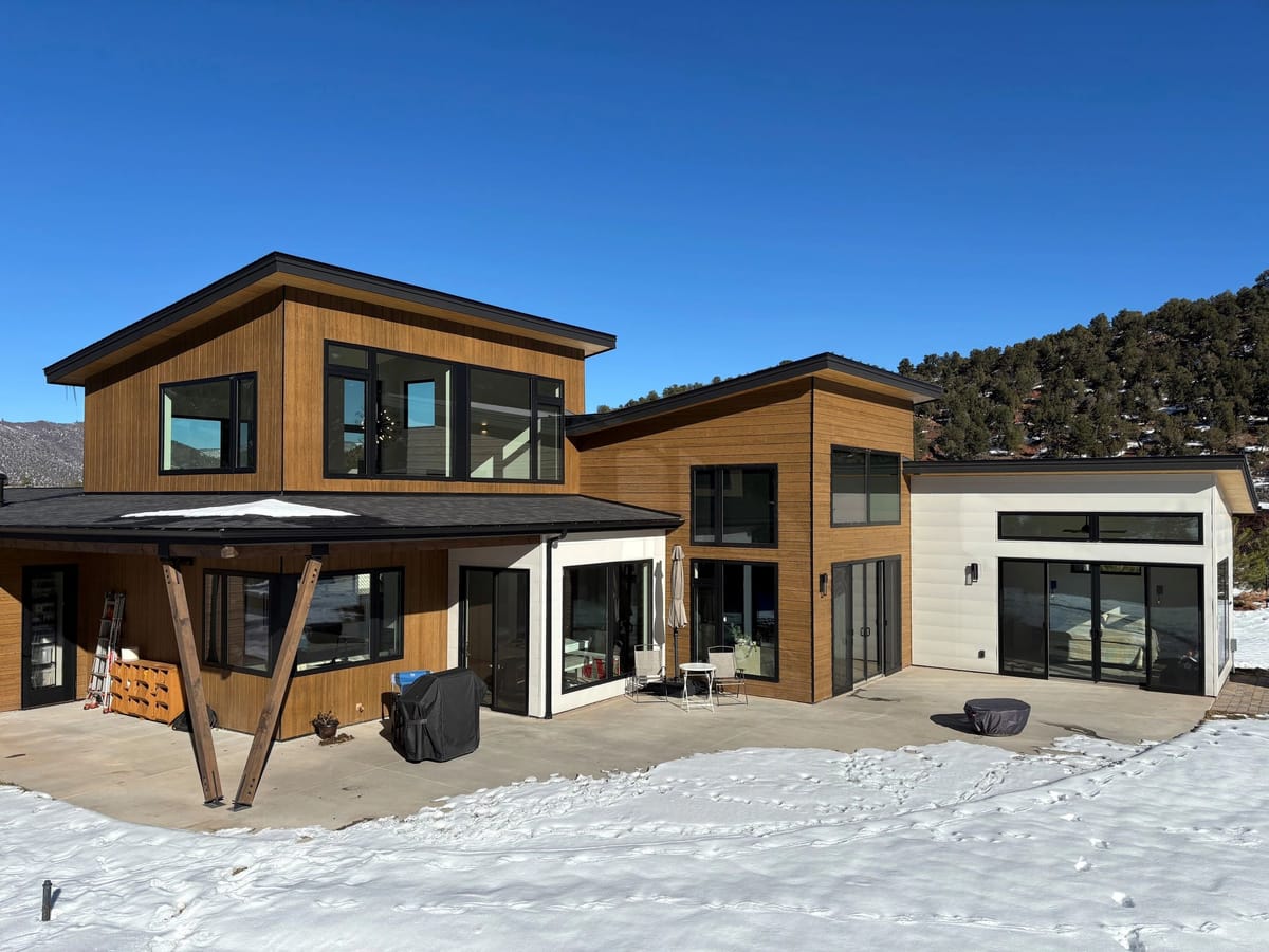 A contemporary timber-and-glass custom home in the snow, built by D.M. Neuman Construction