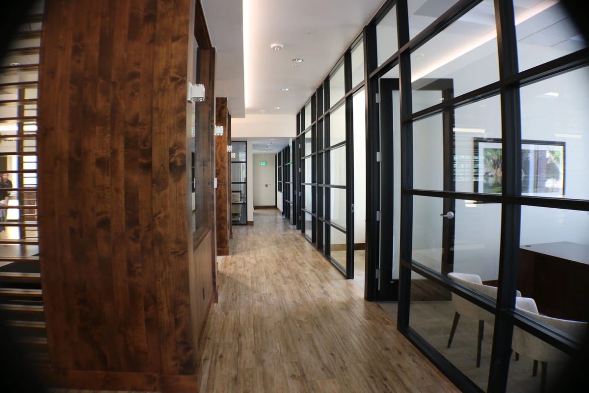 A corridor of glass-walled offices with timber accent walls