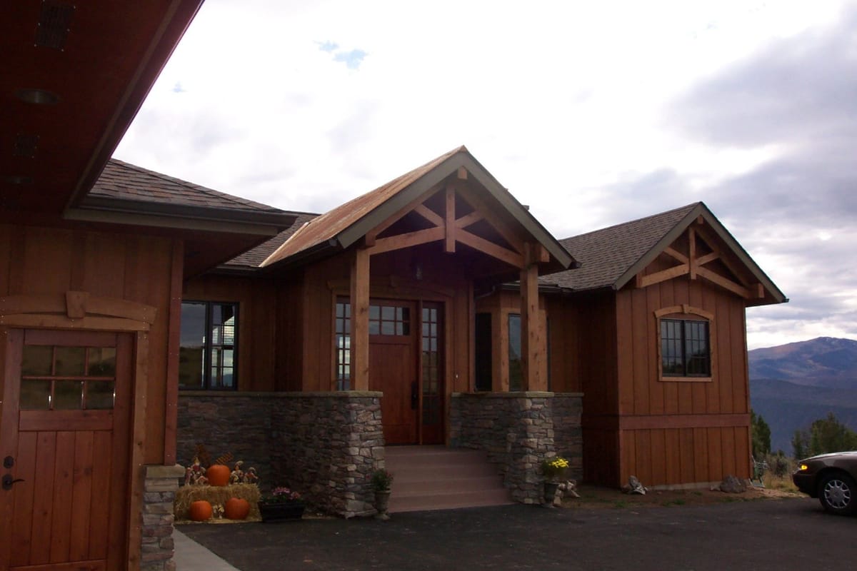 A timber-and-stone custom home with mountains behind