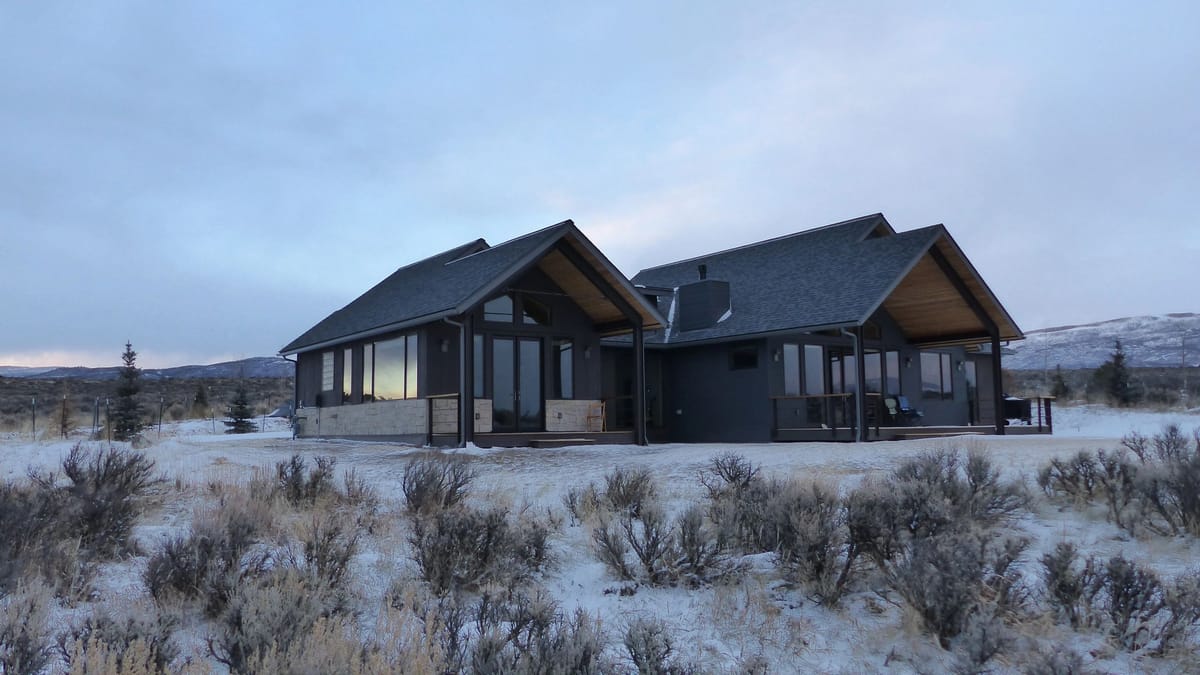 A modern custom home built by D.M. Neuman Construction sitting in a snow-dusted sage meadow under a wide Colorado sky
