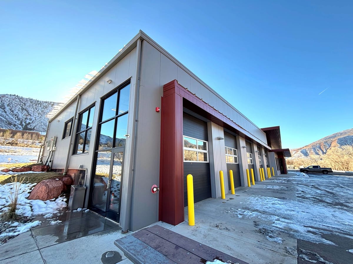 A newly completed commercial service building with roll-up bays and bollards