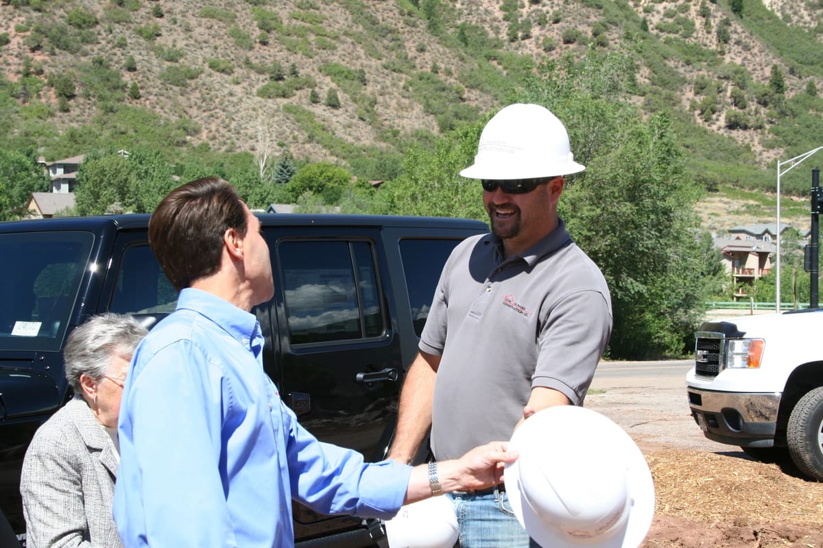 Two men in hard hats shaking hands at a D.M. Neuman groundbreaking in the Roaring Fork Valley