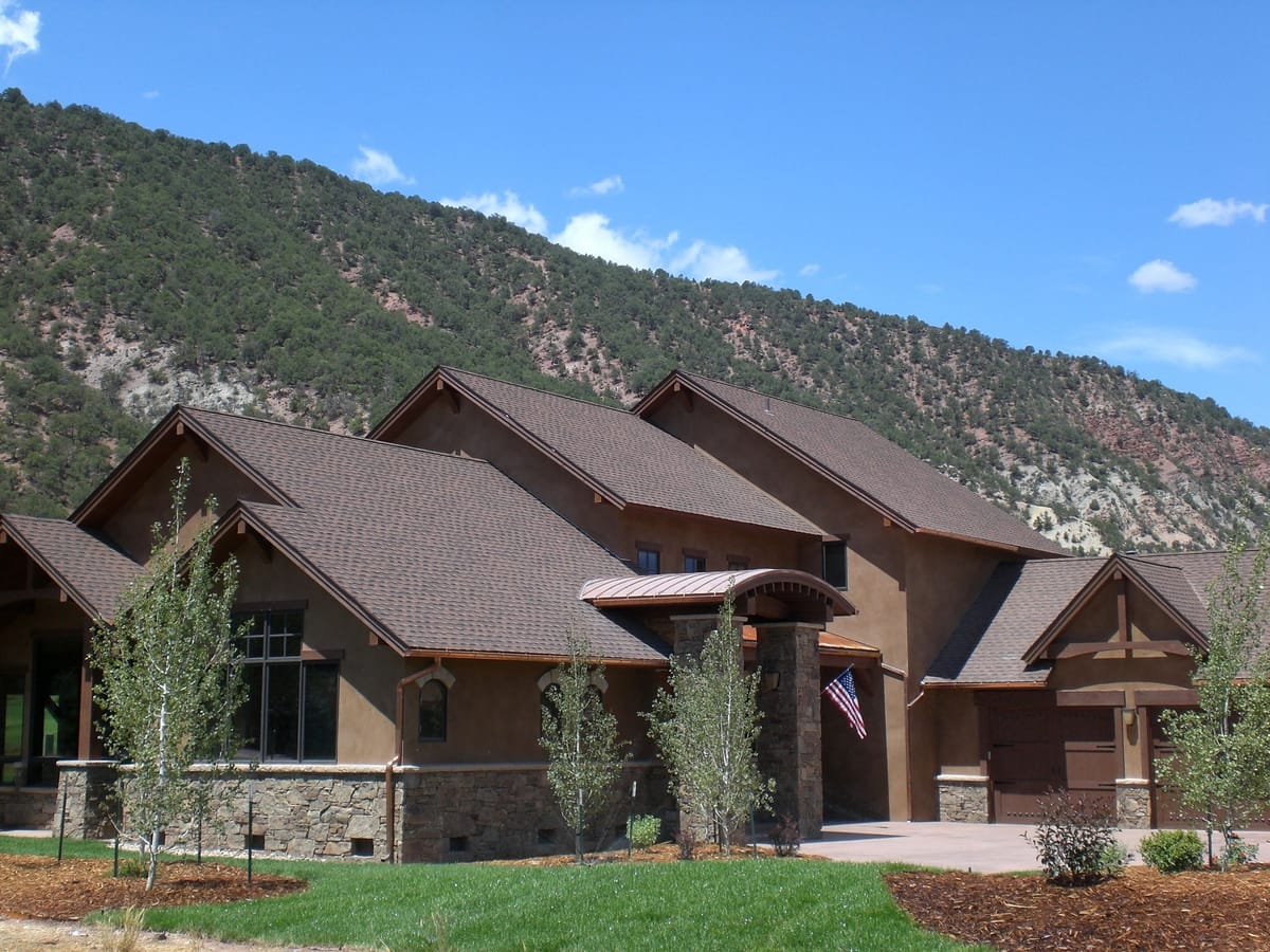 A stone-and-timber custom mountain home with a mountainside rising behind it