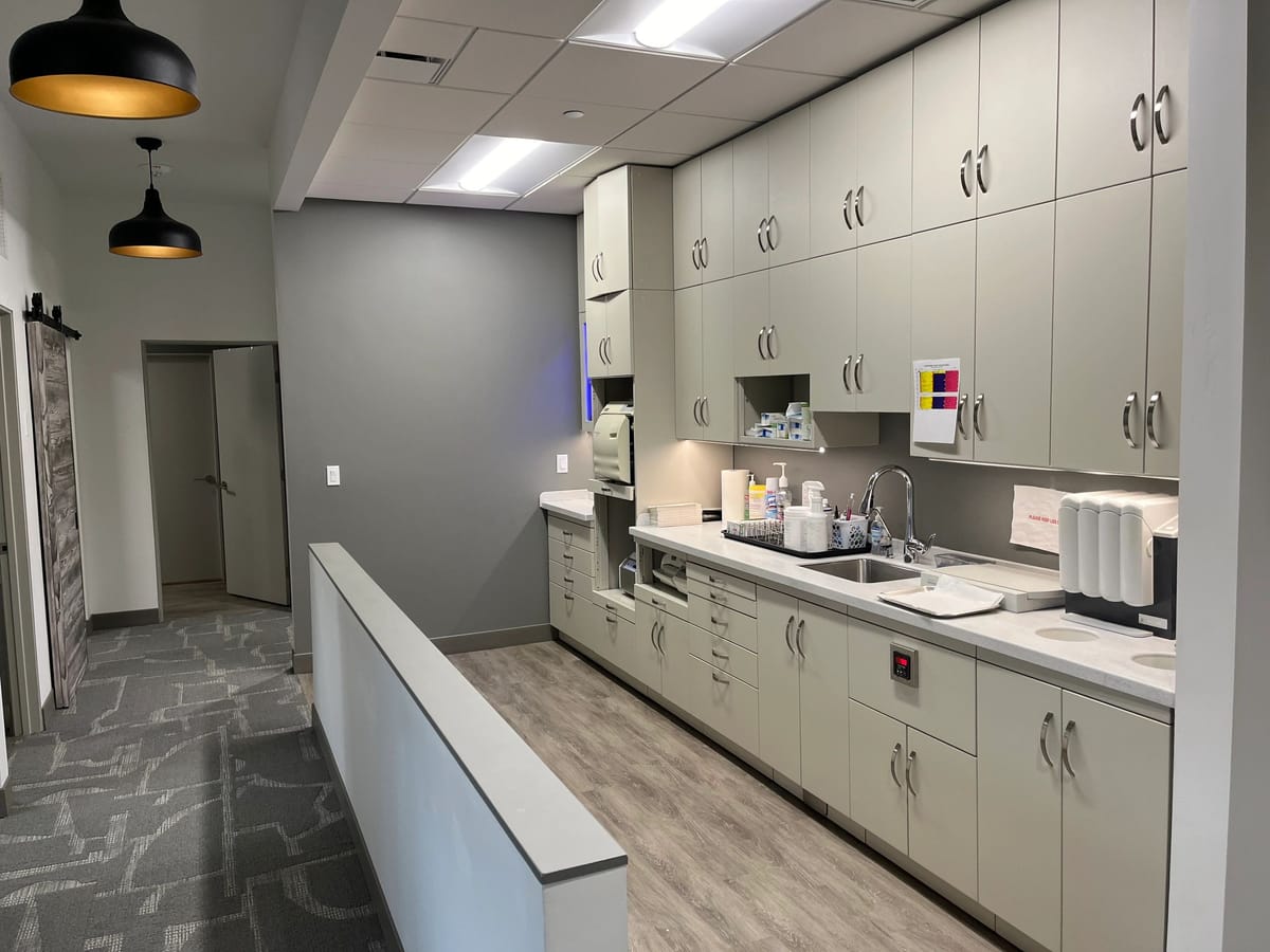A clinical sterilization room with white cabinetry and stainless fixtures