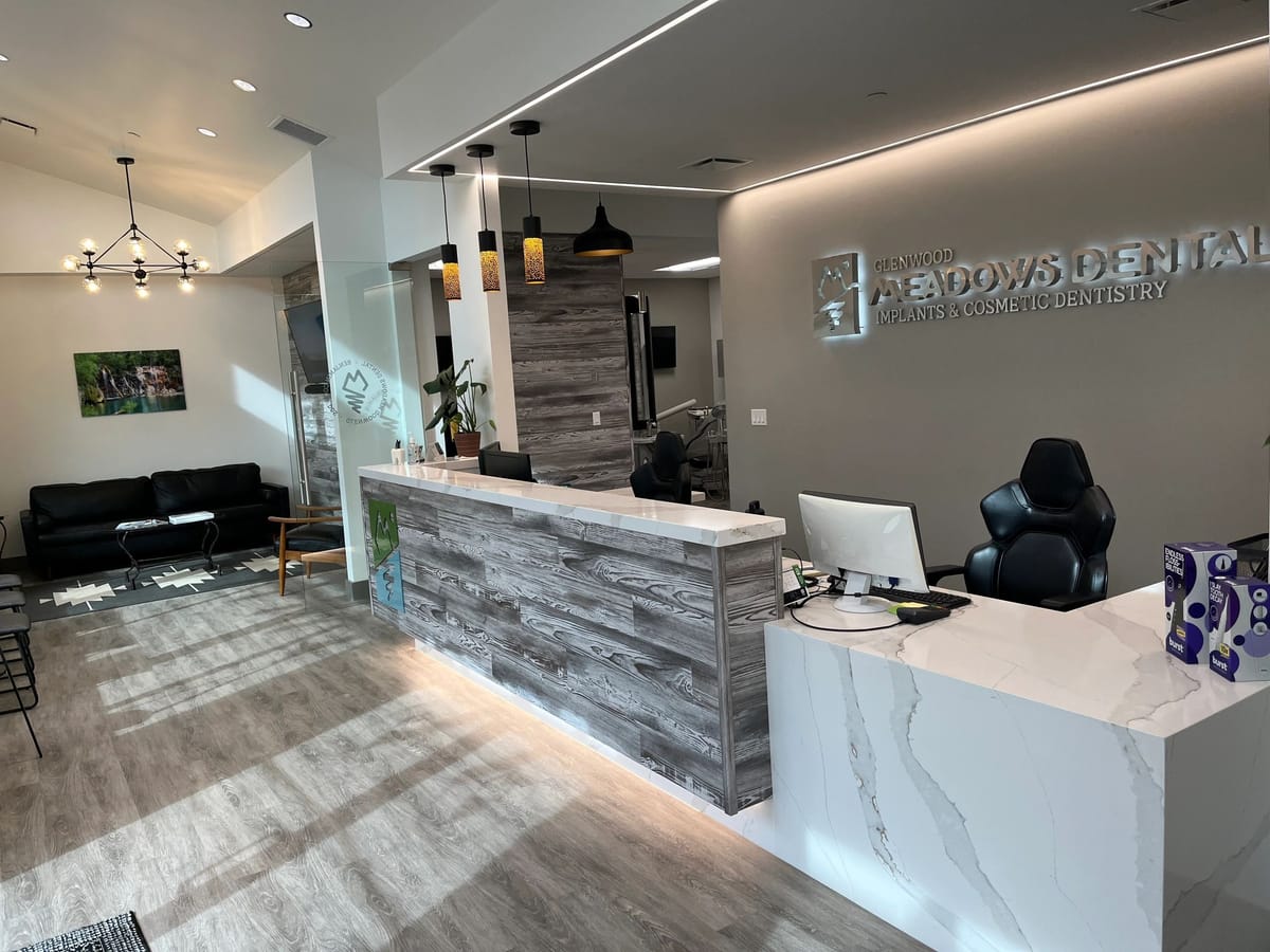A dental practice reception desk in stone and reclaimed timber under pendant lighting