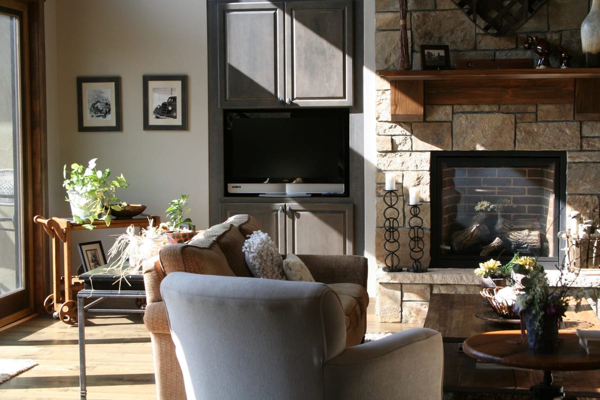 A remodeled living space with a stone fireplace, built-in shelving and soft furnishings