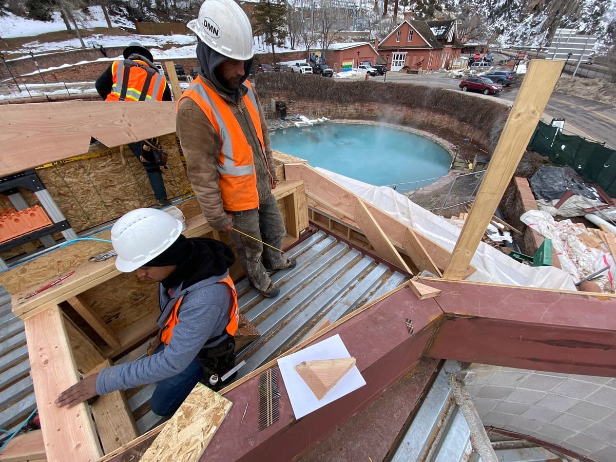 D.M. Neuman crew members in hard hats and high-visibility vests working on a hot-springs pool structure