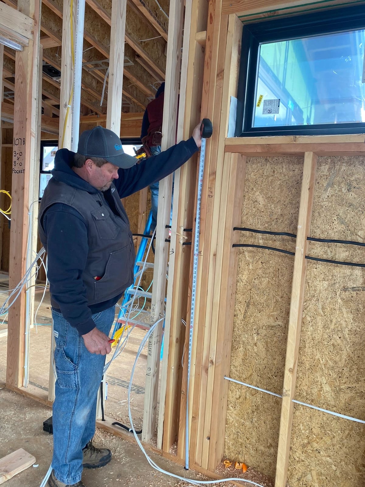 A superintendent checking framing dimensions against the drawings