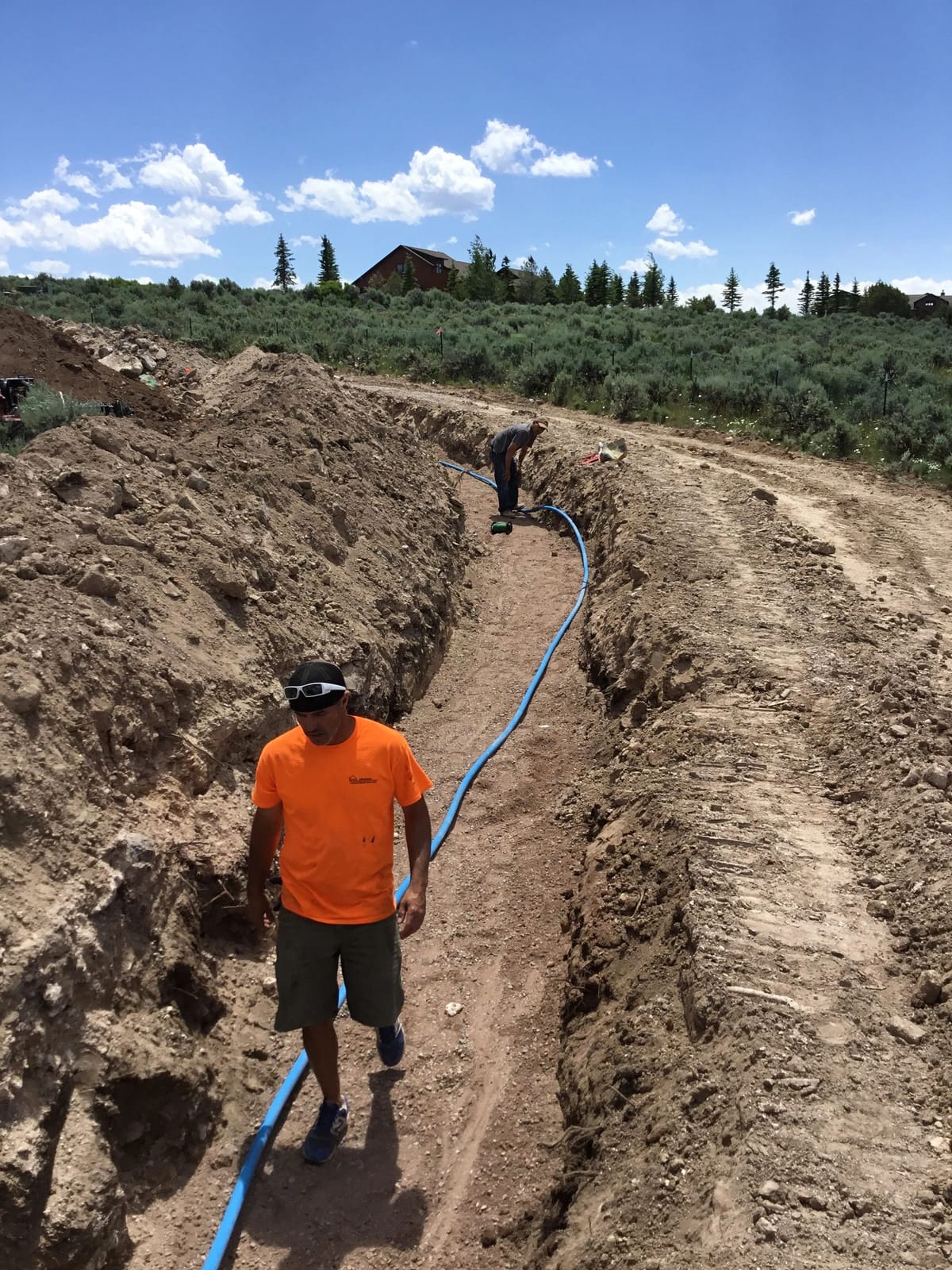 A crew member laying utility line in a trench on a Colorado jobsite