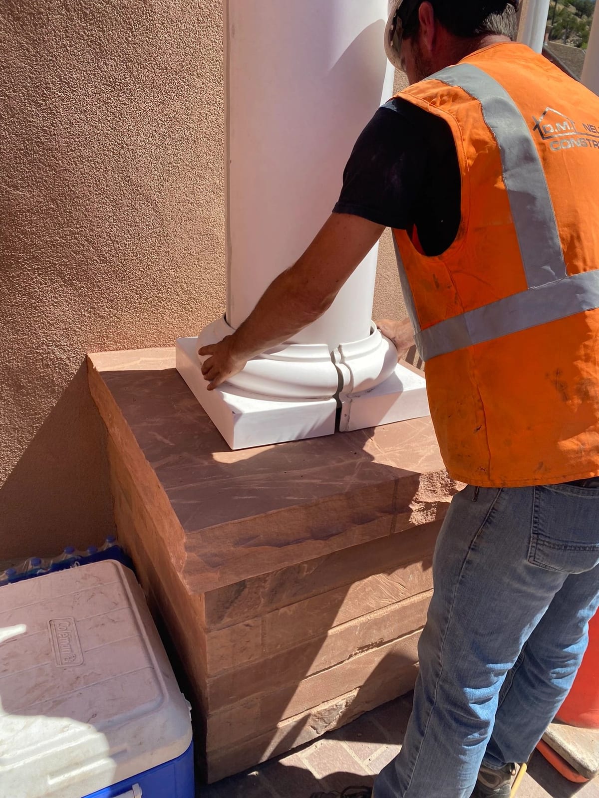A finish carpenter fitting a column base on a stone stair