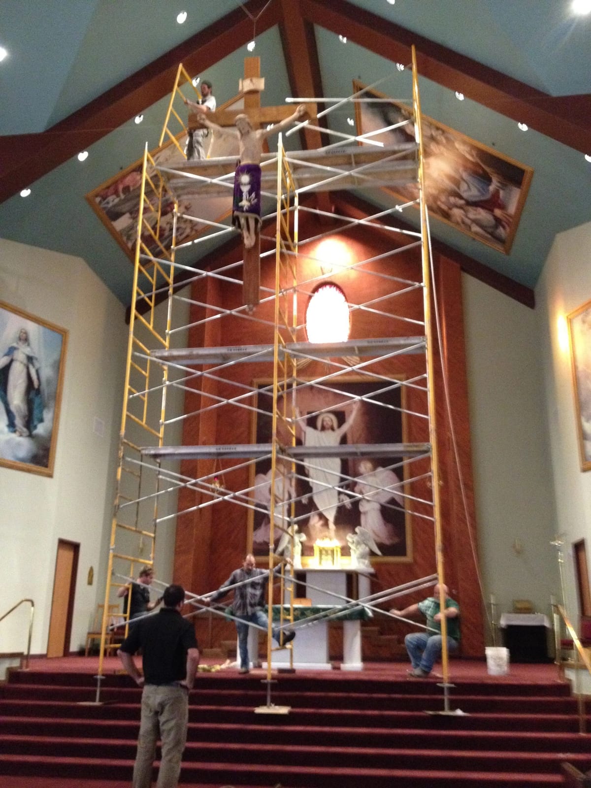 A crew member on scaffolding finishing a vaulted great-room ceiling
