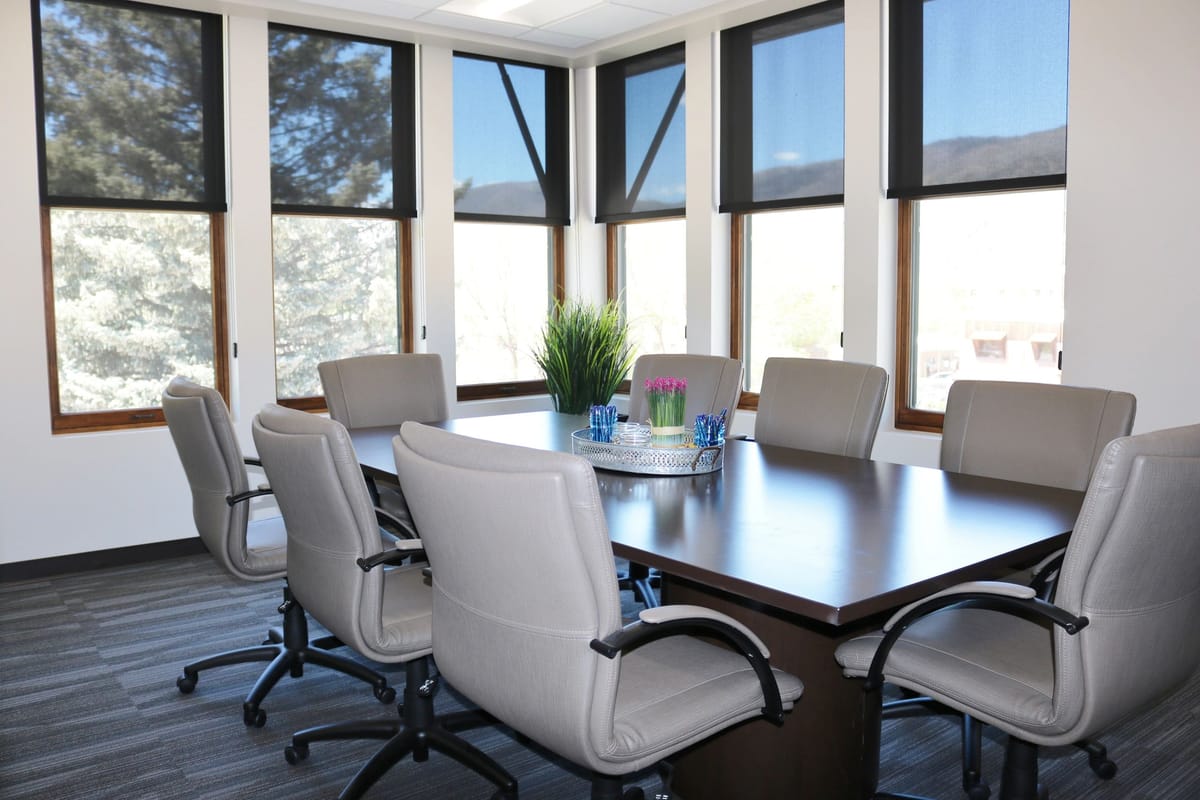A sunlit corner conference room with a long table and valley views