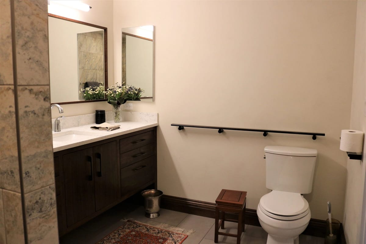 A remodeled bathroom with a stone-topped vanity and a tiled shower surround