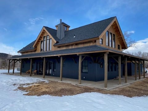 A timber barn-style outbuilding with a covered porch in the snow