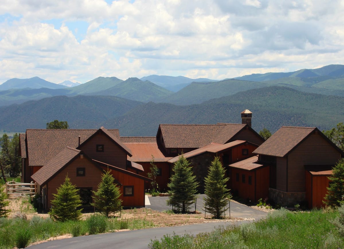 A shingled mountain home with the Elk Range in the distance