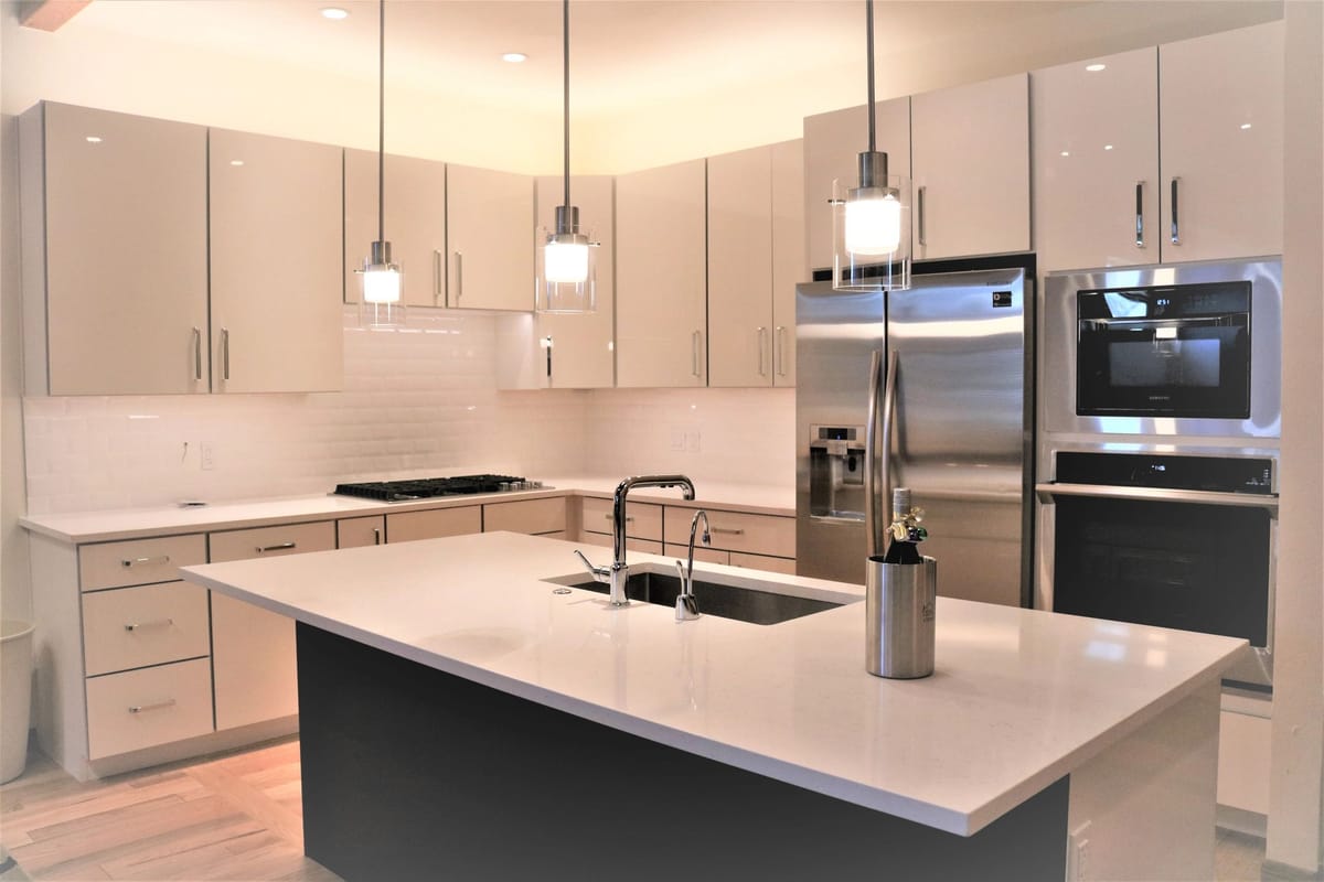 A white custom kitchen with a waterfall island and pendant lighting