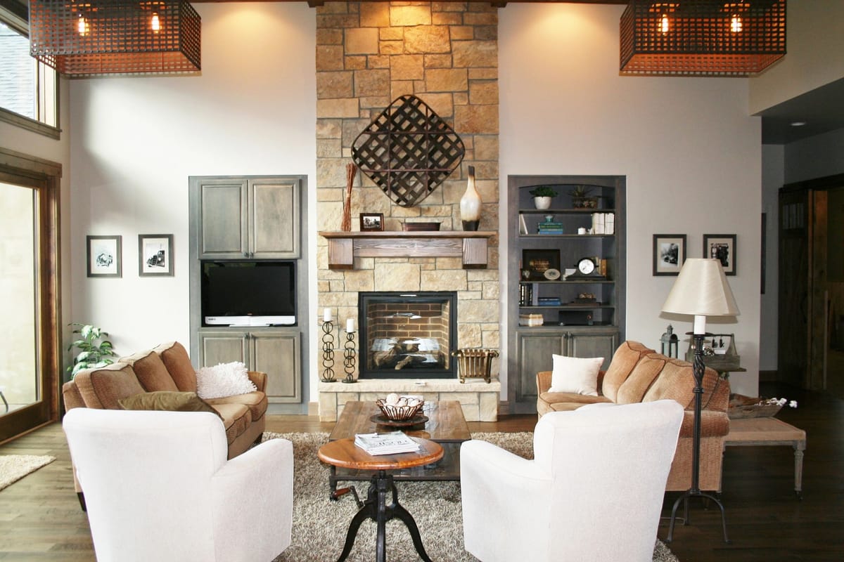 A great room with a stone fireplace, built-in cabinetry and a coffered timber ceiling