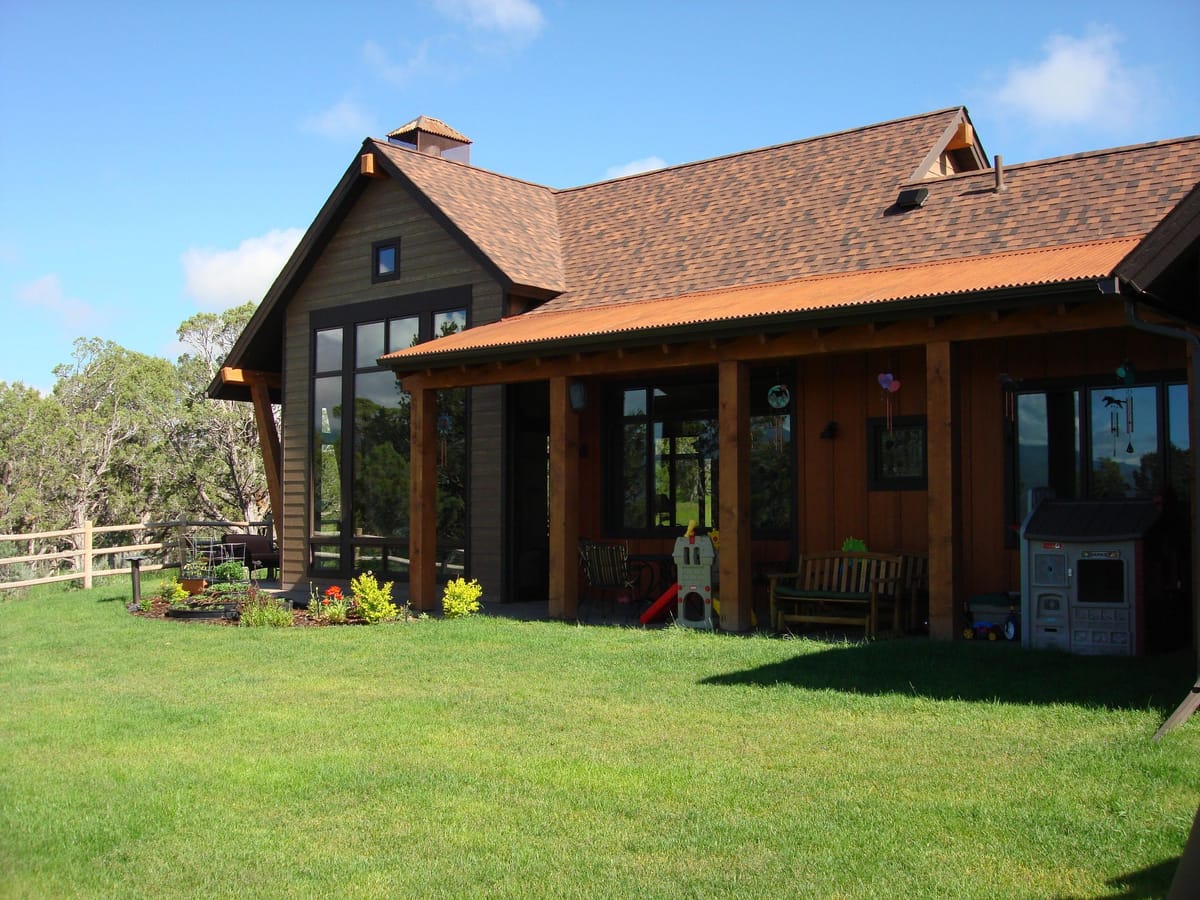 A timber-framed mountain home with covered porches and a green lawn