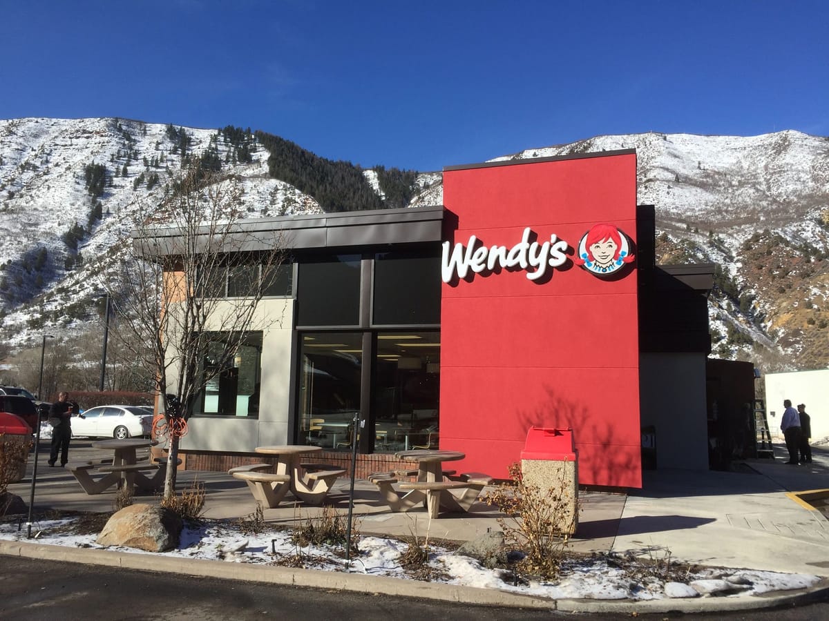 A completed Wendy's restaurant with a snow-covered mountain ridge behind it