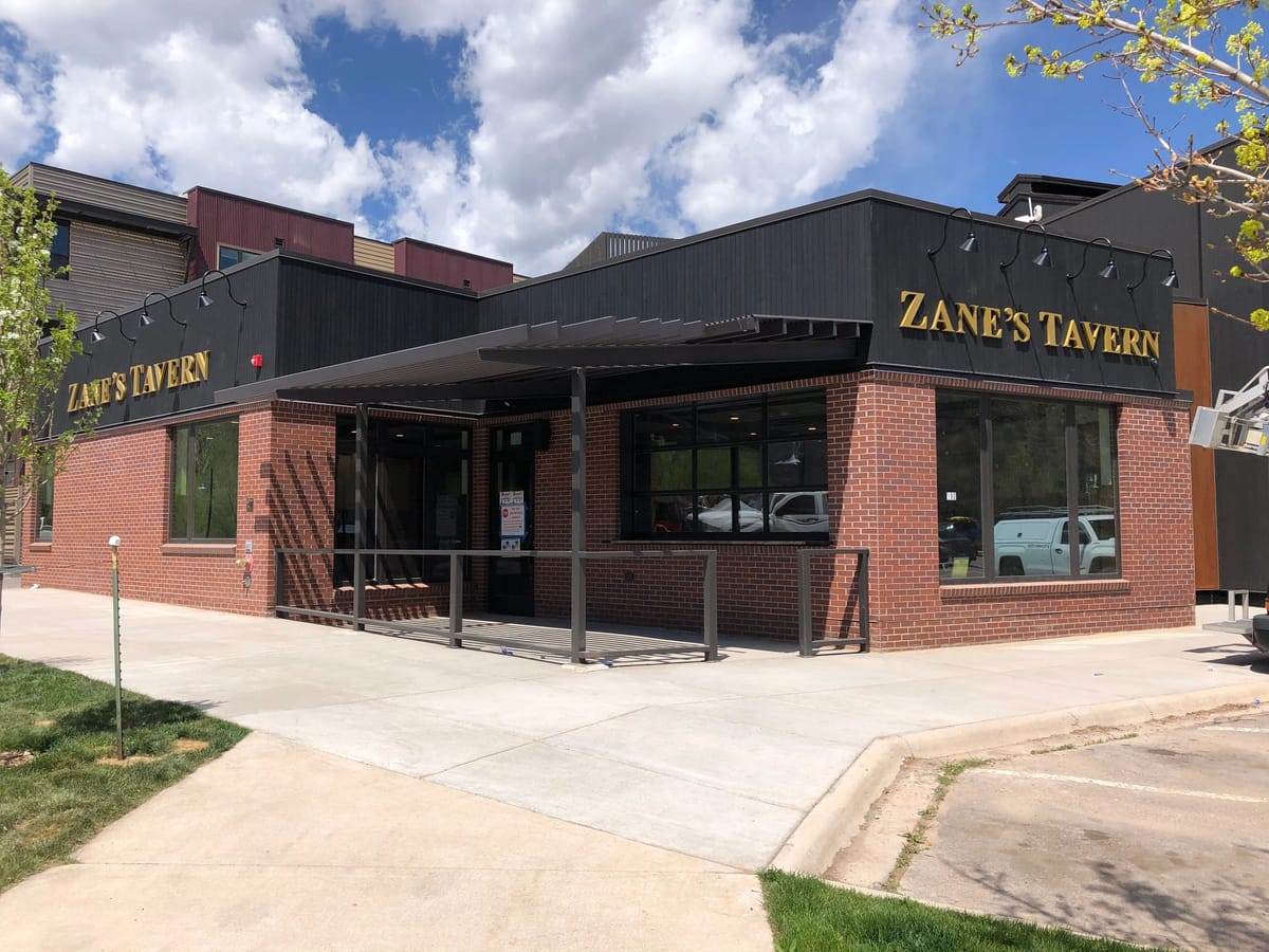 The brick and dark-clad exterior of Zane's Tavern on a Glenwood Springs street corner